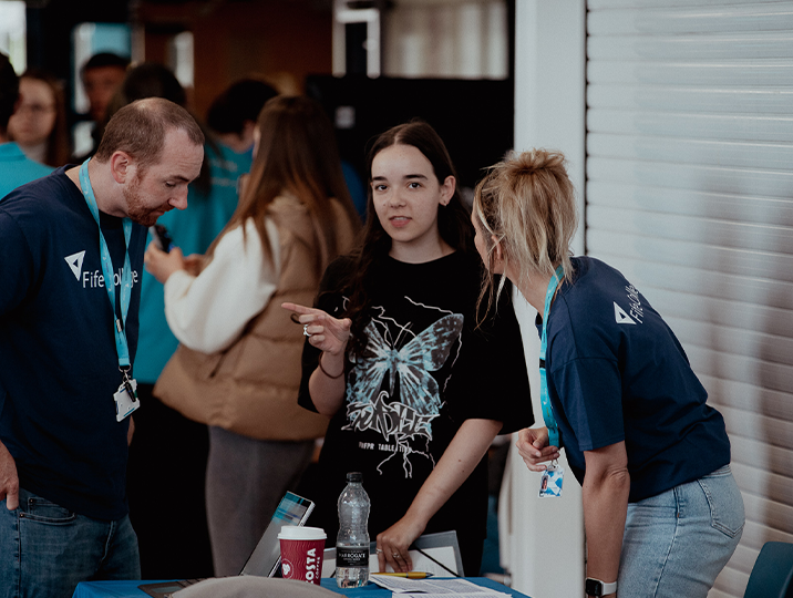 two staff members talking to student at event