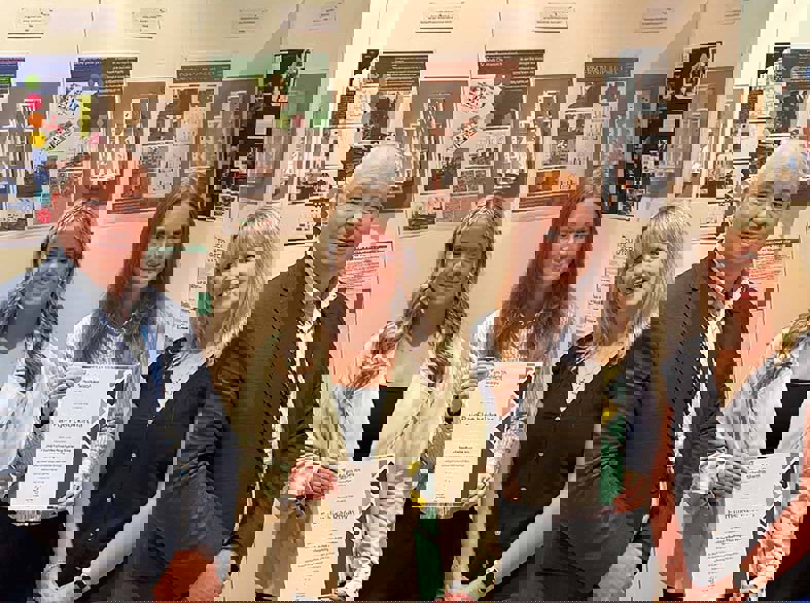 Two students, with certificates, standing with two members of college staff