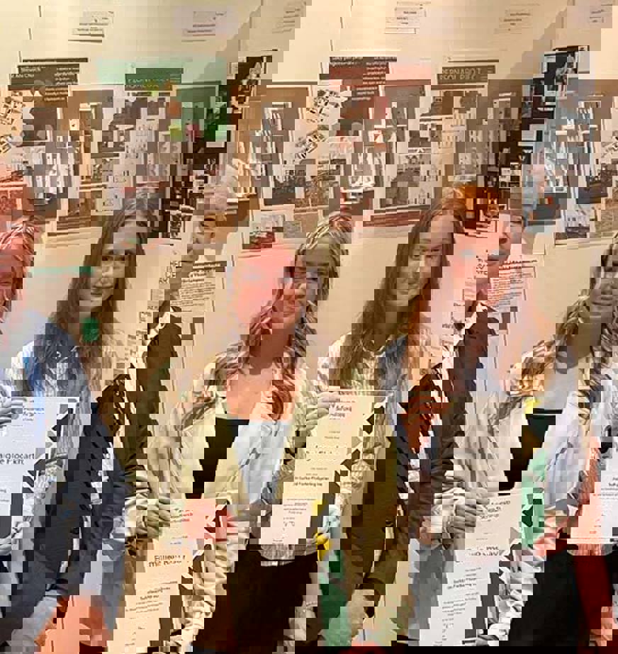 Two students, with certificates, standing with two members of college staff