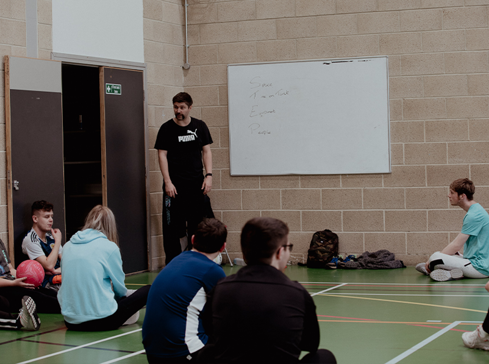 sport lecturer and students in gym hall