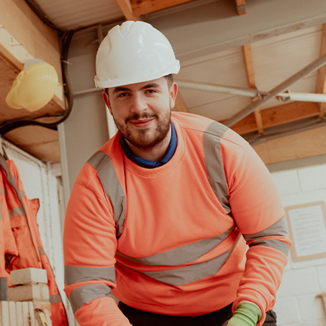 male brickwork student smiling in camera wearing ppe