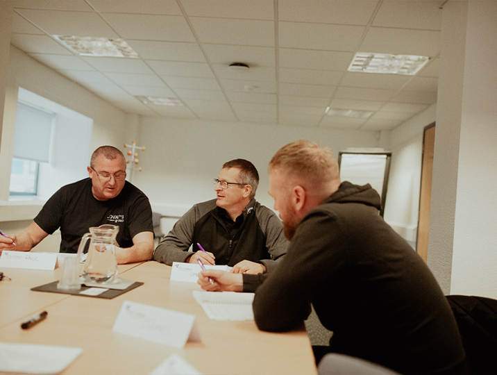 iosh students in classroom at desk writing and talking