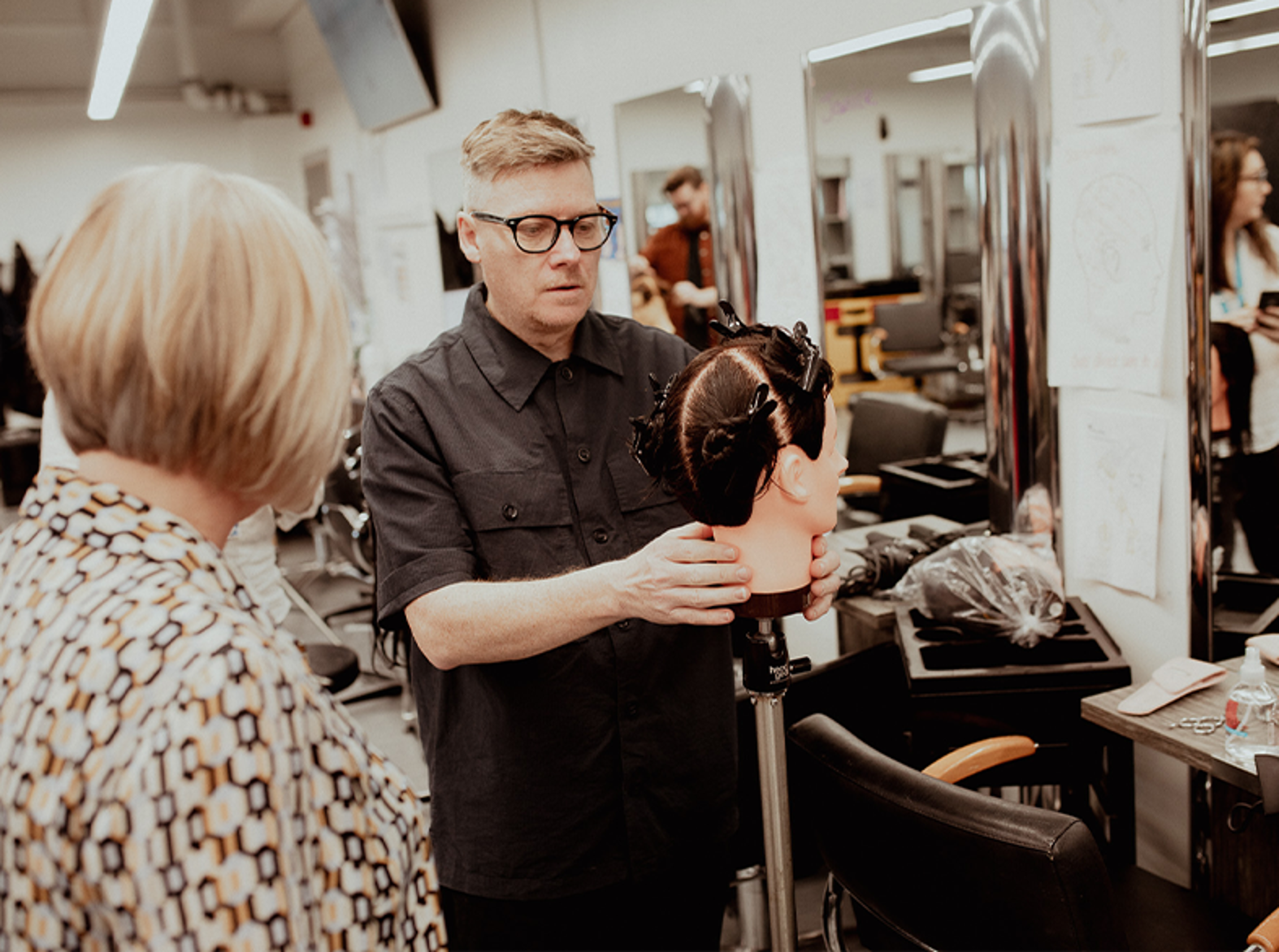 male hairdressing lecturer demonstrating on mannequin