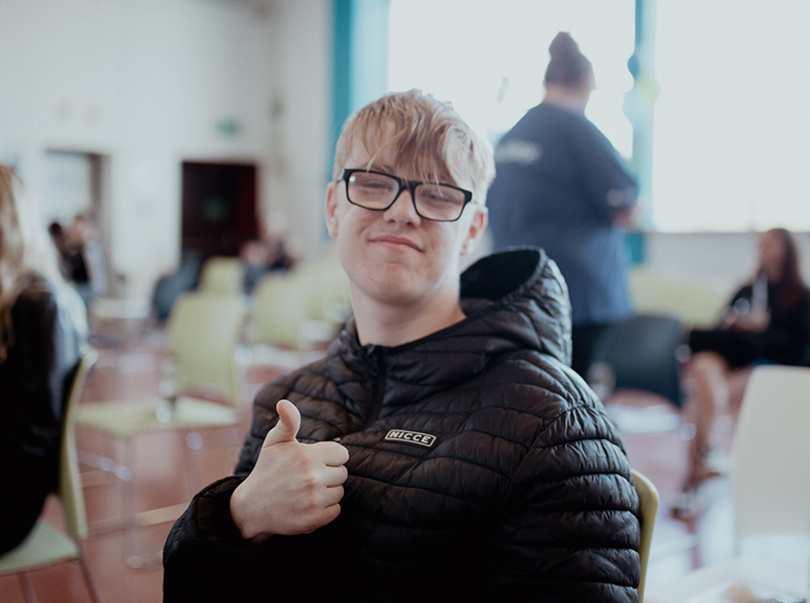 male student with thumbs up smiling at camera