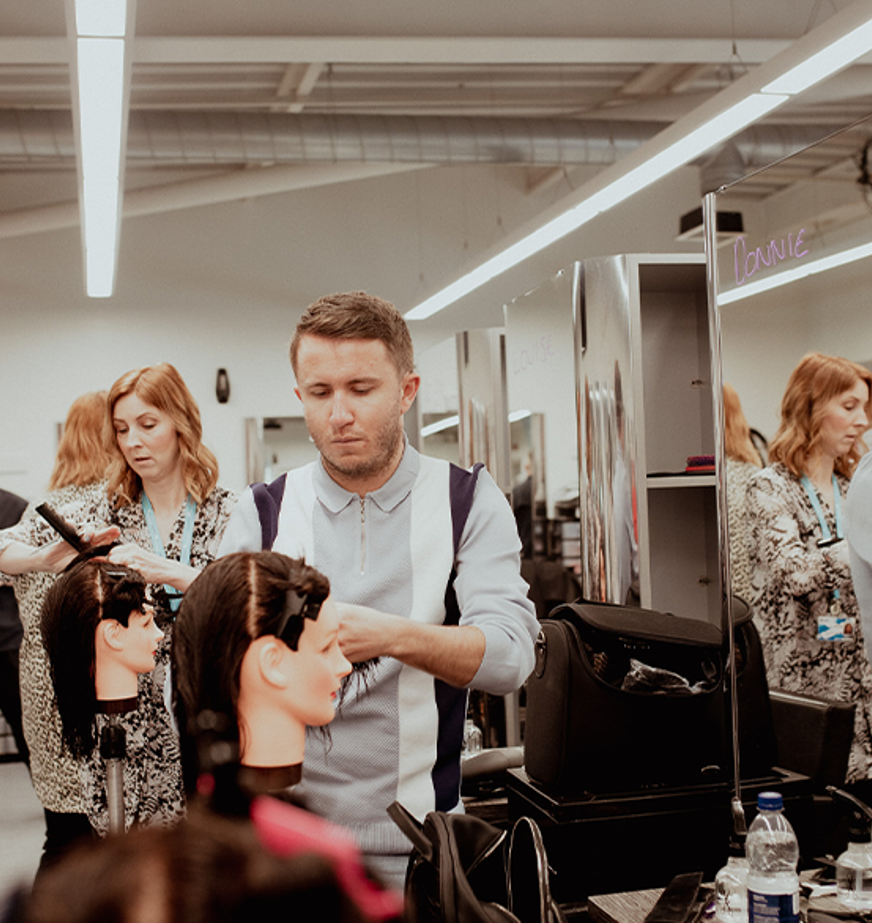 male hairdressing student working on mannequin head 