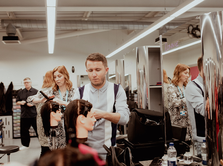 male hairdressing student working on mannequin head