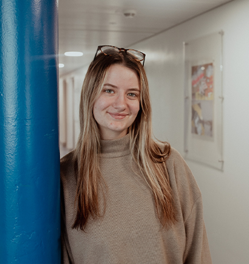 girl leaning on pillar smiling at camera